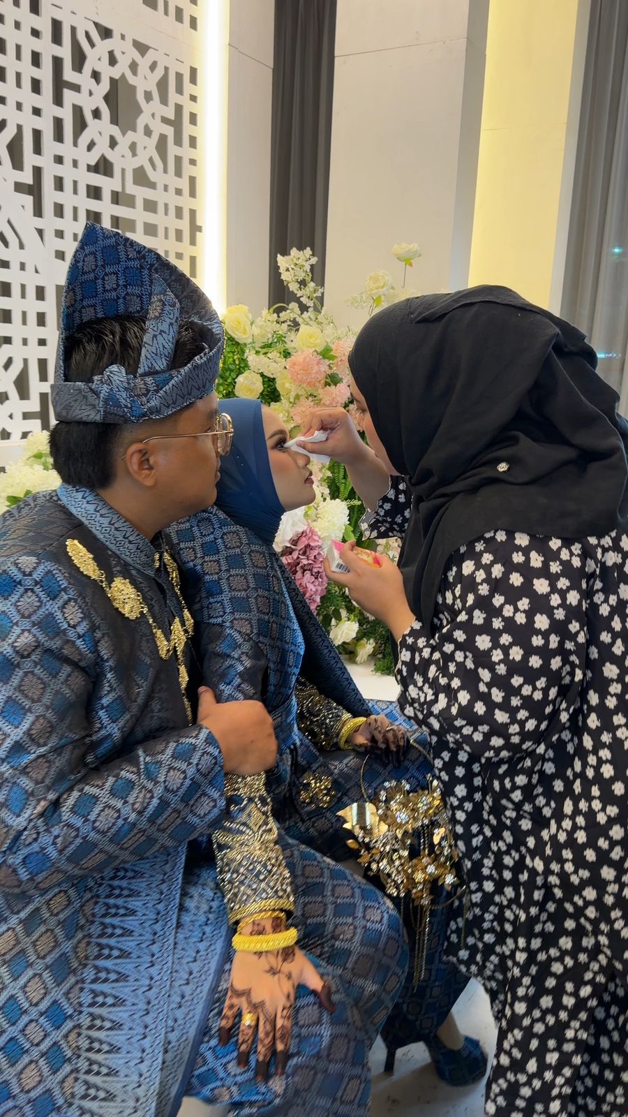 Alya touching up the bride at the pelamin